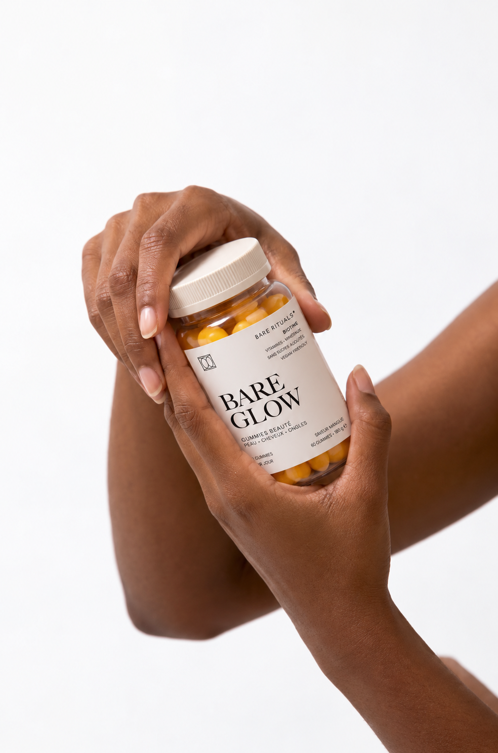 Mains tenant un pot de gummies beauté Bare Glow de Bare Rituals, à la biotine, pour la peau, les cheveux et les ongles.